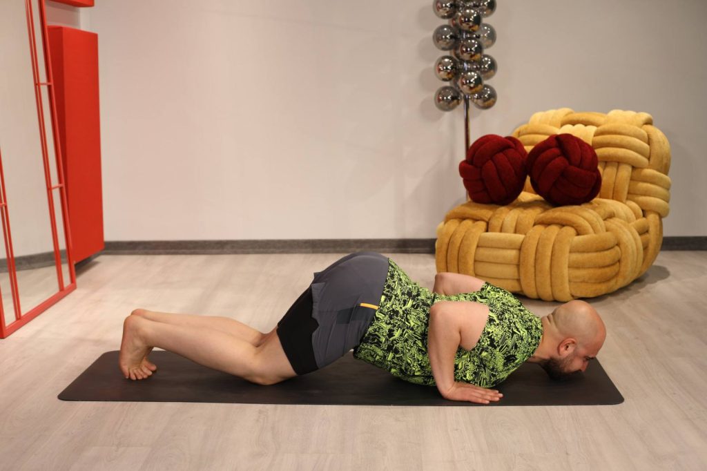 فرم نهایی وضعیت هشت نقطه در یوگا؛ سینه و چانه روی زمین، لگن بالاتر و زانوها و پنجه پا تکیه‌گاه